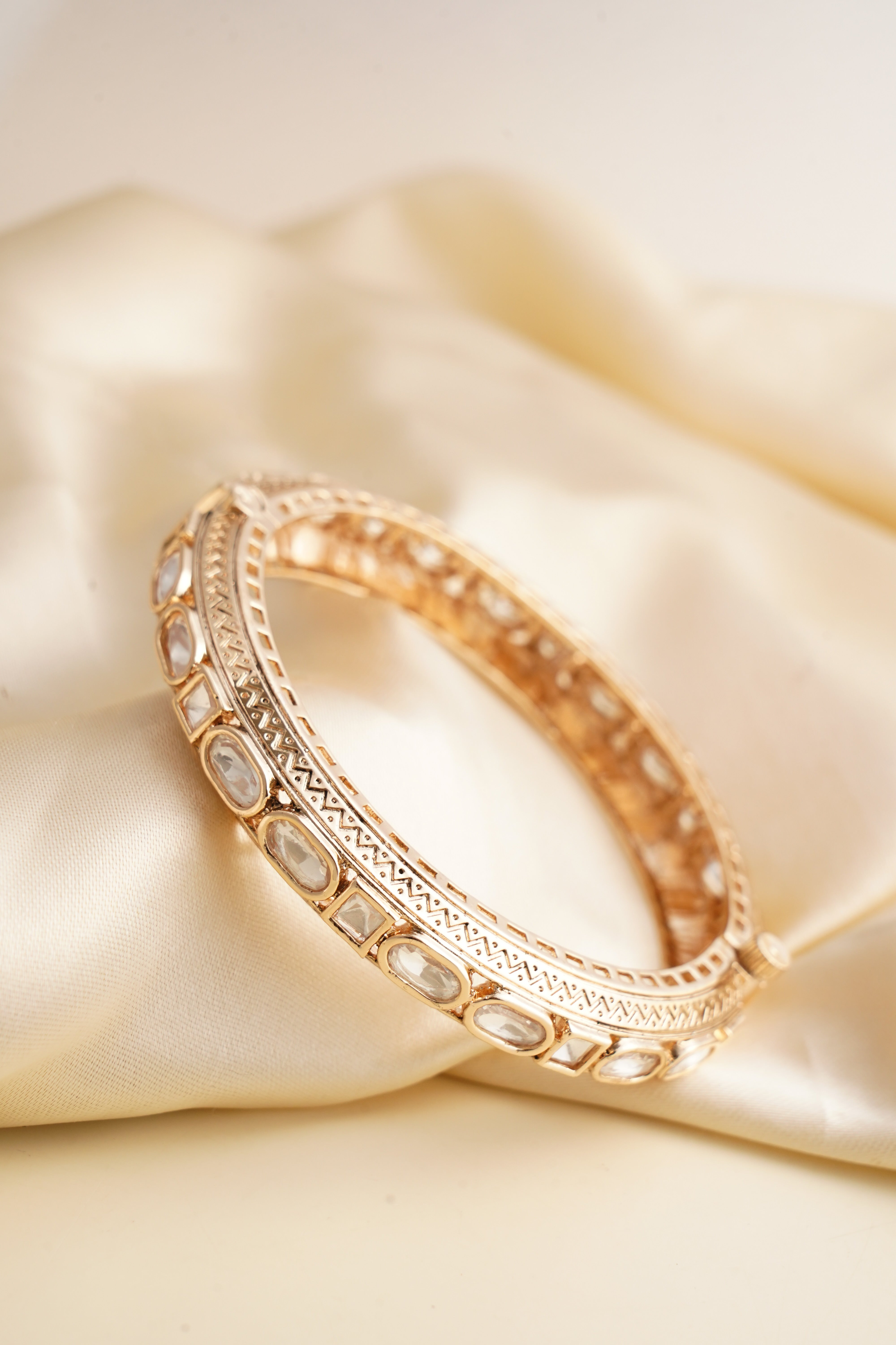 Angled view of antique polki bangle with uncut oval and square stones and engraved edges